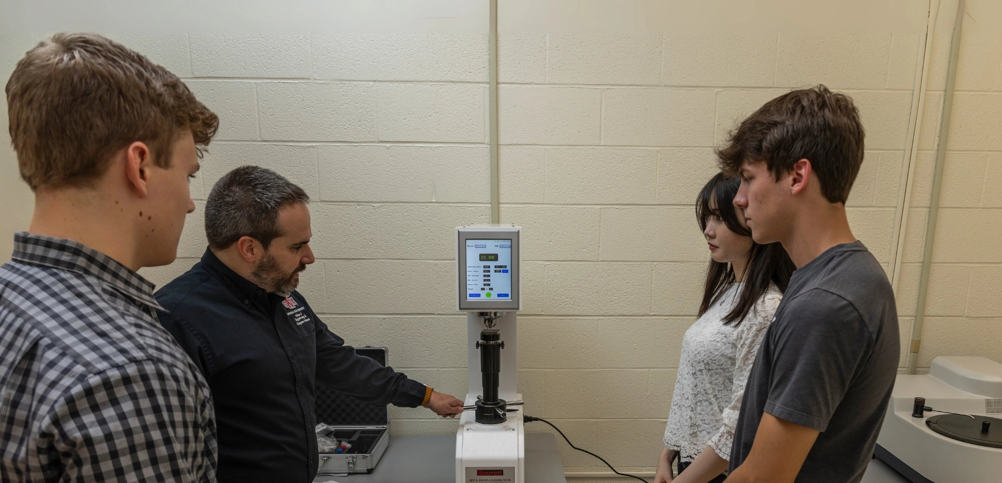 Students and professor going over manufacturing equipment operations.