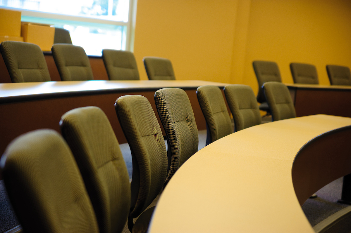 Empty modern A-State classroom with curved desks and padded chairs arranged in tiers.