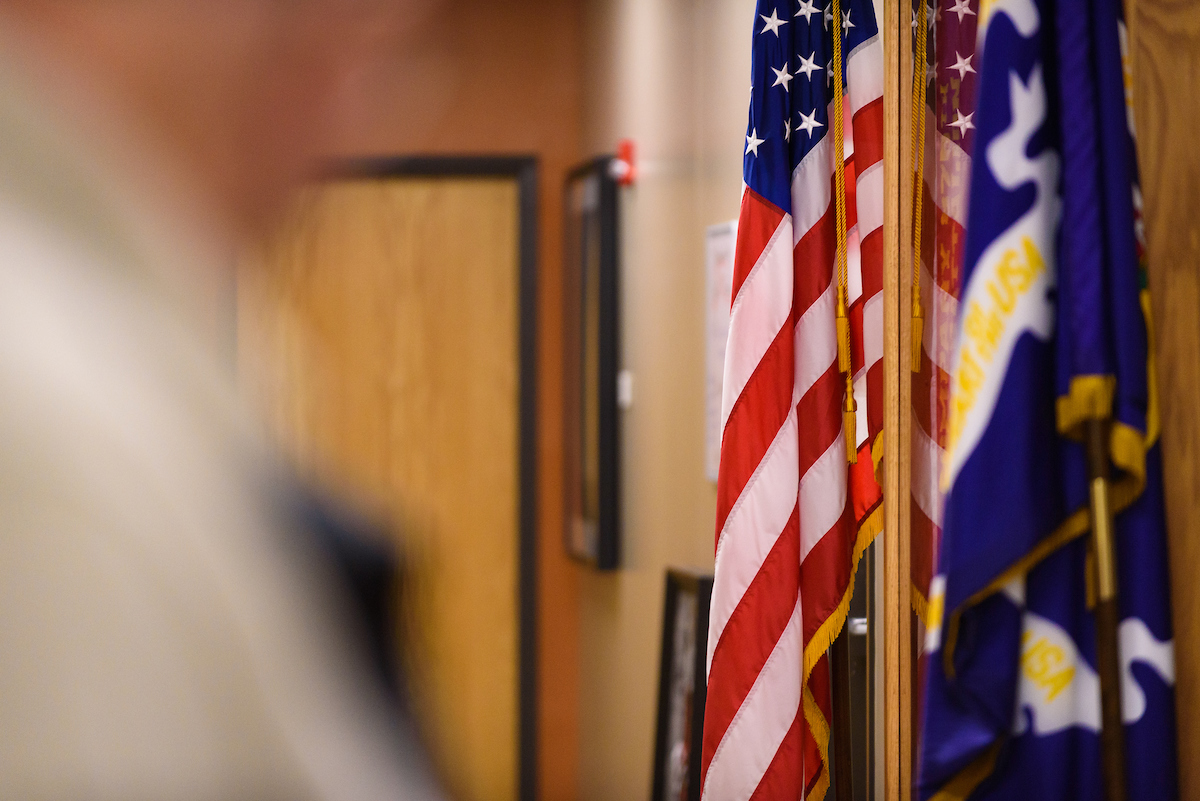 Close-up of American and military flags displayed in a hallway.