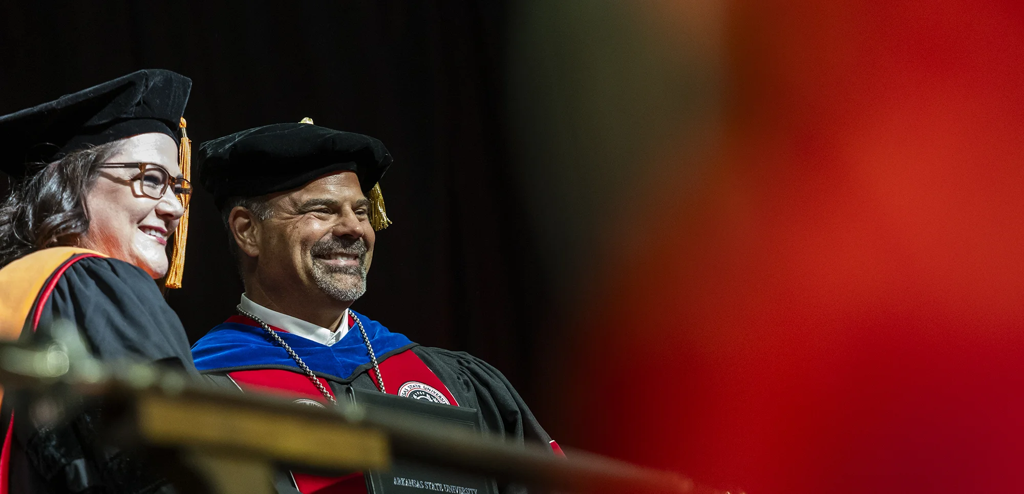 Dr. Todd Shields smiling with doctoral graduate at commencement ceremony.