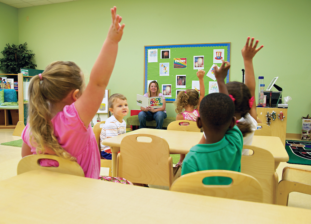 Students raising their hands in an early childhood class.
