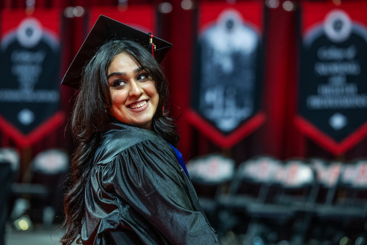 A graduate smiles over her shoulder during Fall Commencement.