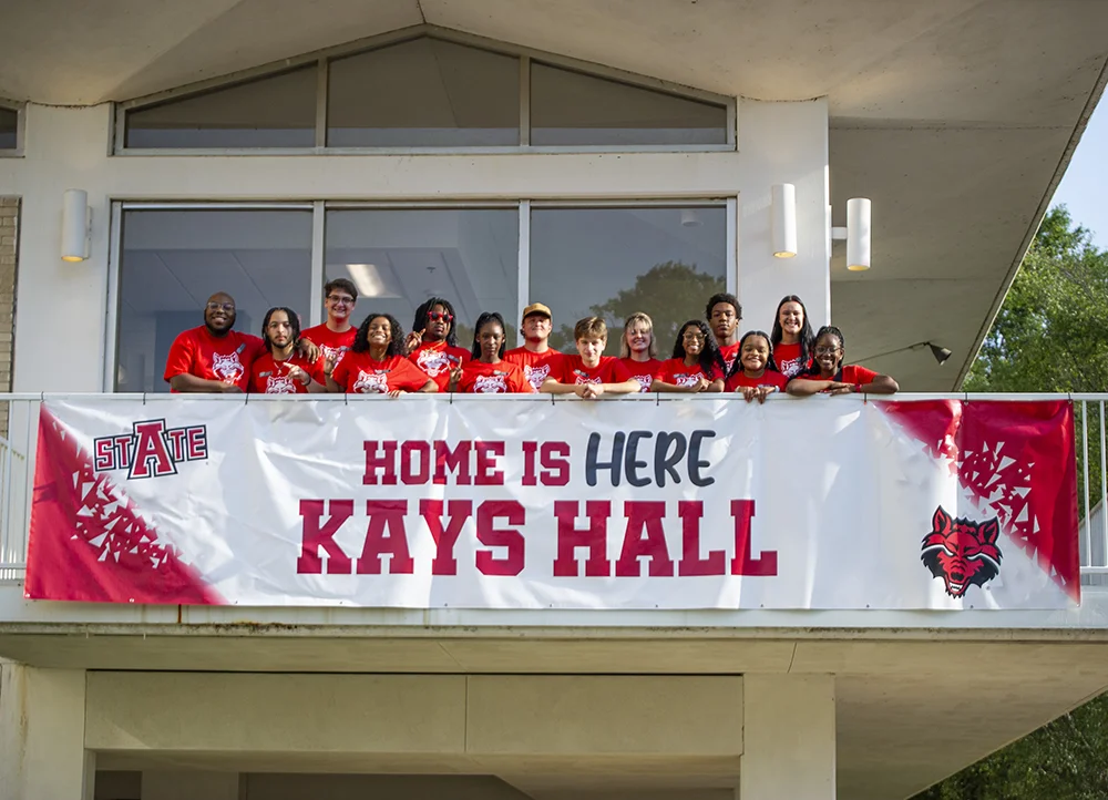 Students smiling with a "Welcome to Kays Hall" banner.
