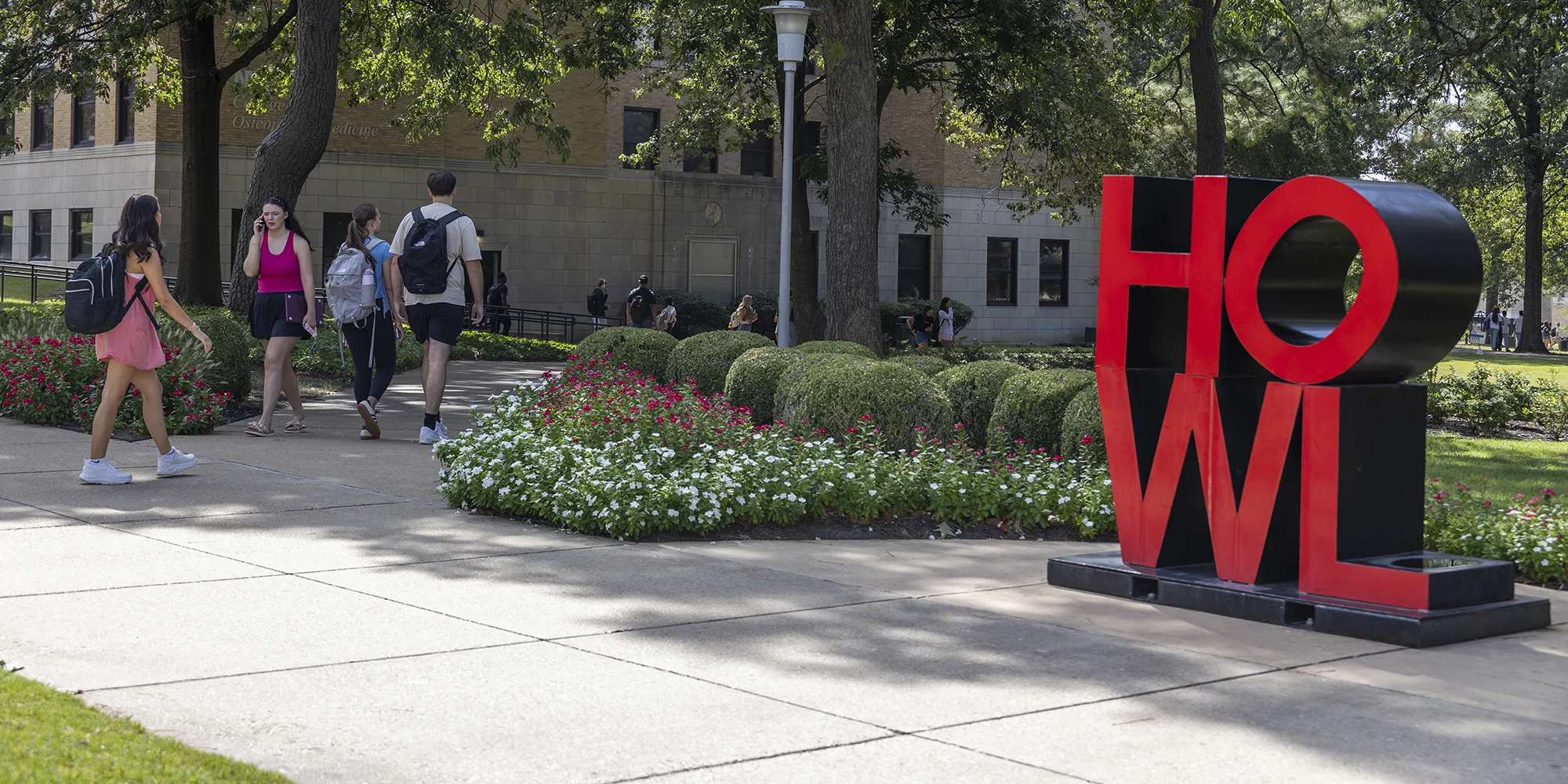 Students on campus walking by the HOWL sculpture.