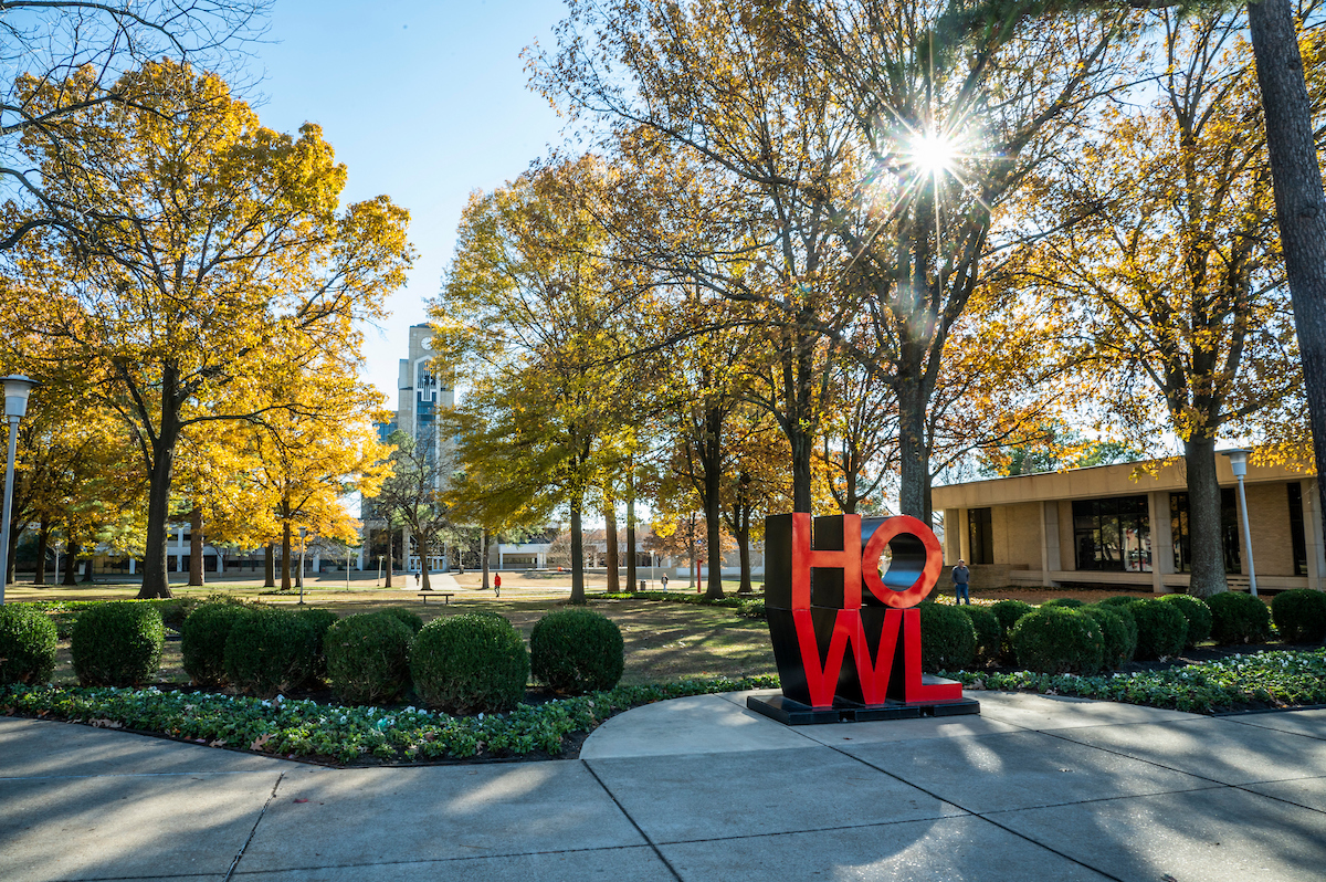 The HOWL word statue on the Arkansas State University campus during the fall, with the Dean B. Ellis library in the background