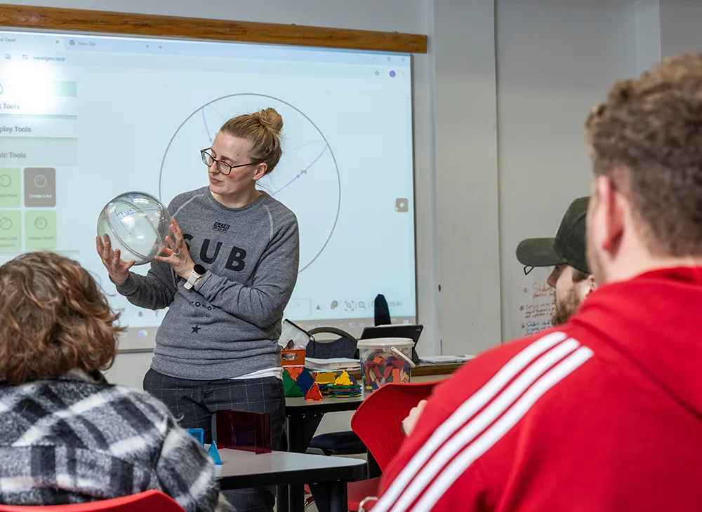 Professor using a 3D ball to demonstrate a problem to class.