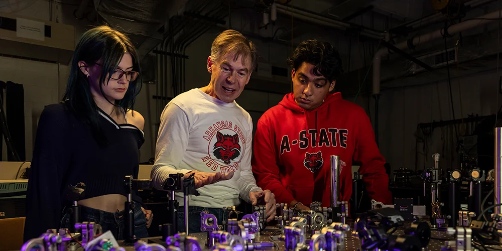 A Physics professor demonstrating a lab to students.
