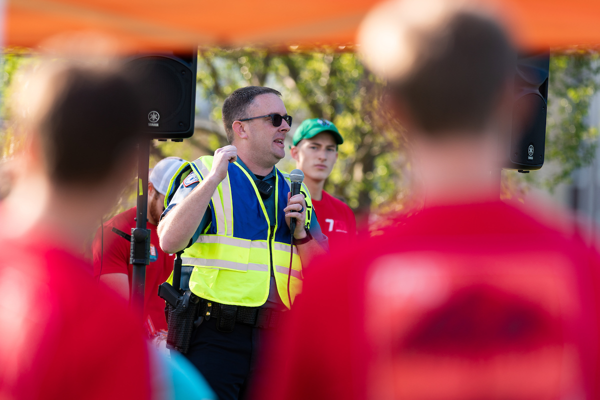 A police officer talks to a crowd on a microphone at a campus event.