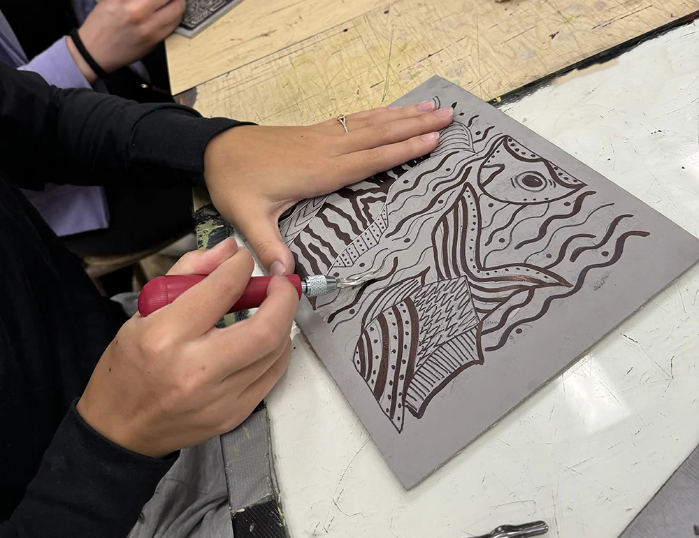 A student working on a printmaking relief.