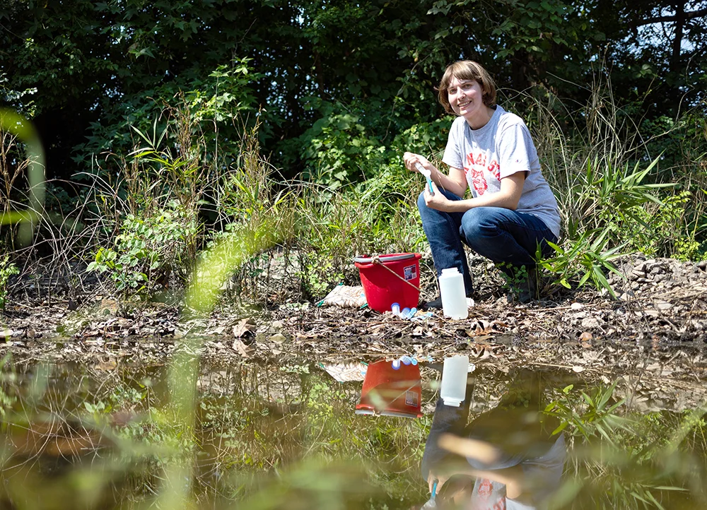 A-State professor collecting samples from a river for testing.