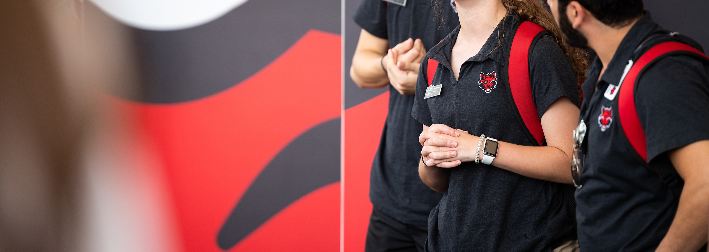 A close-up of people wearing A-State polo shirts.