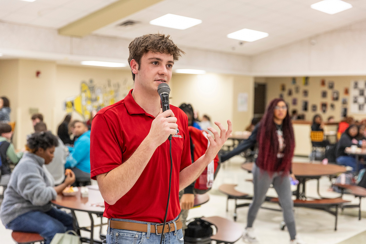 An A-State student worker talks on a microphone to prospective high school students
