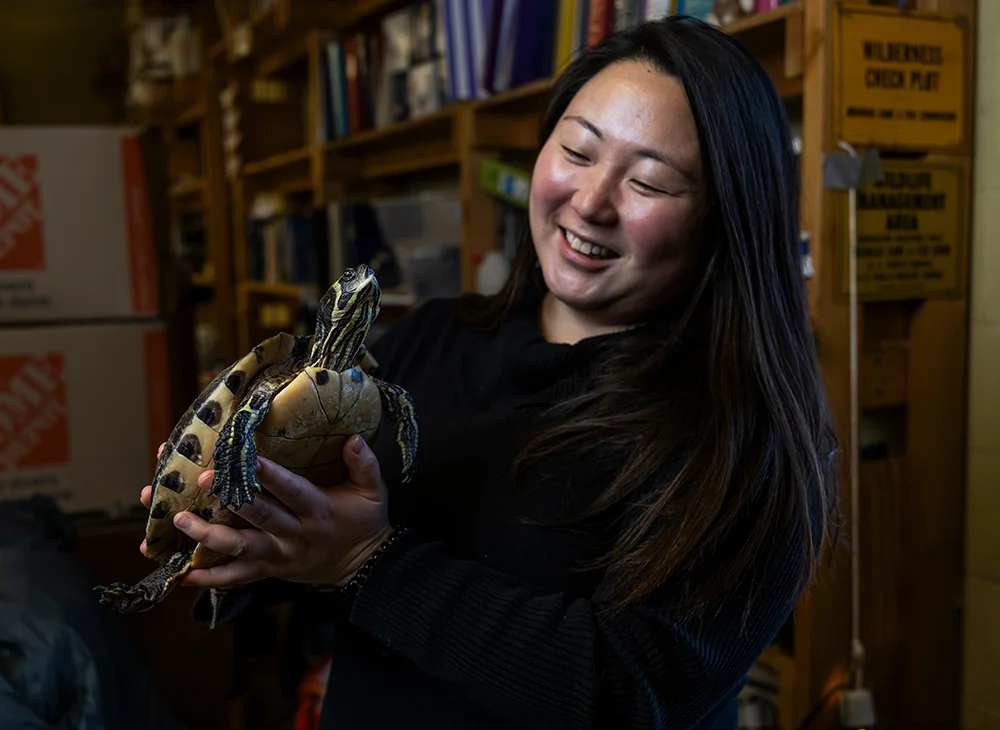 A smiling student holding a turtle.