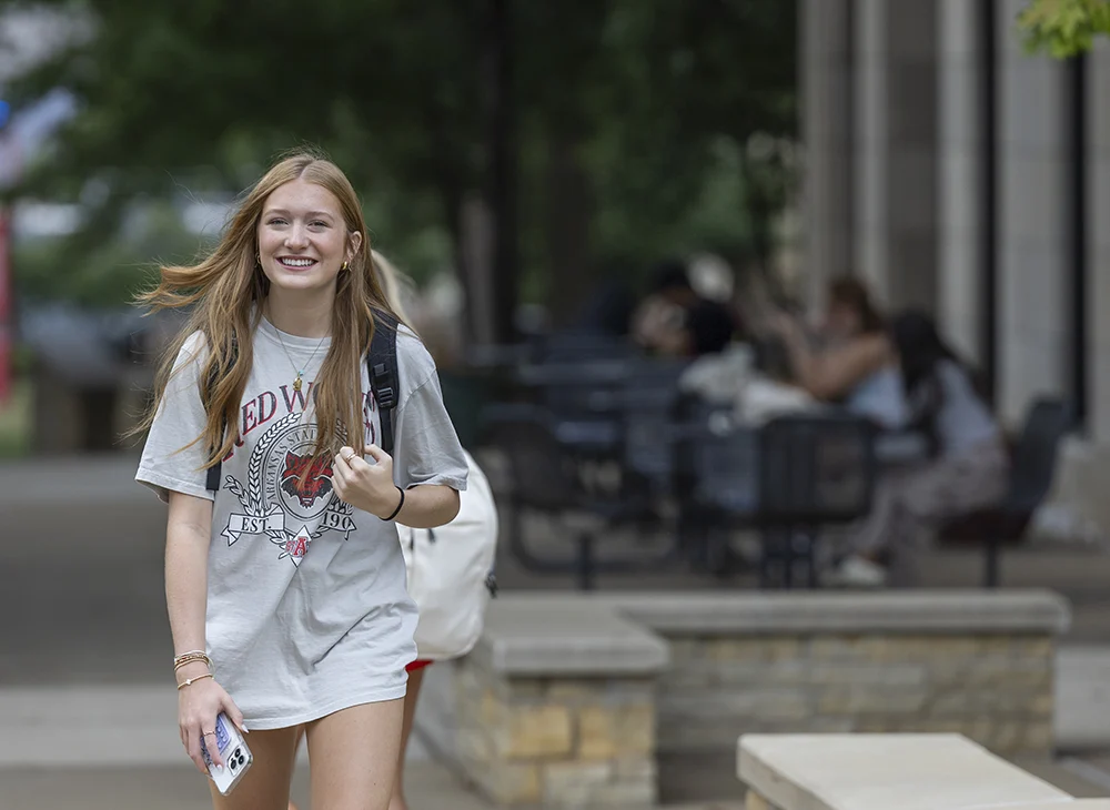Student in Red Wolves t-shirt walking on campus.