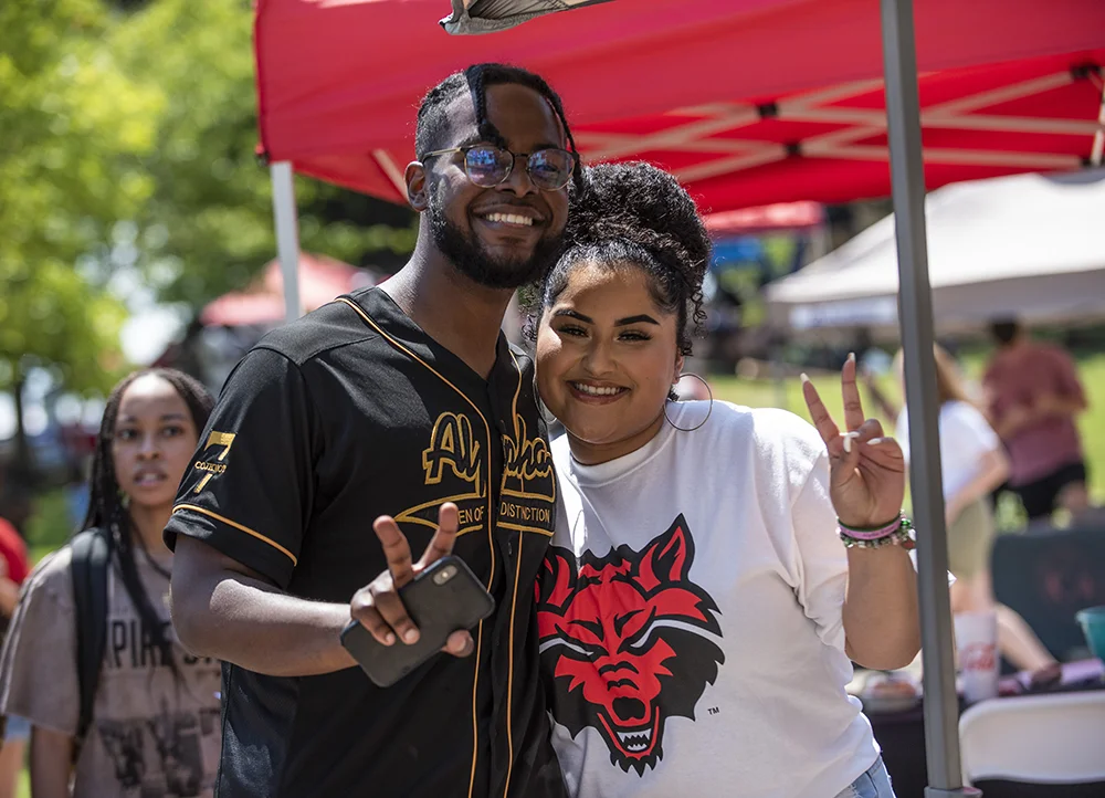 Two students giving peace signs at an A-State event.
