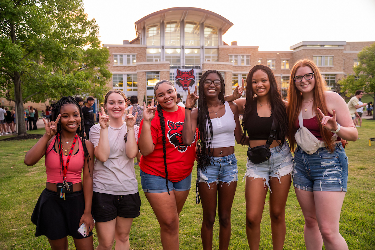 Group of A-State students pose during a sunset campus event.