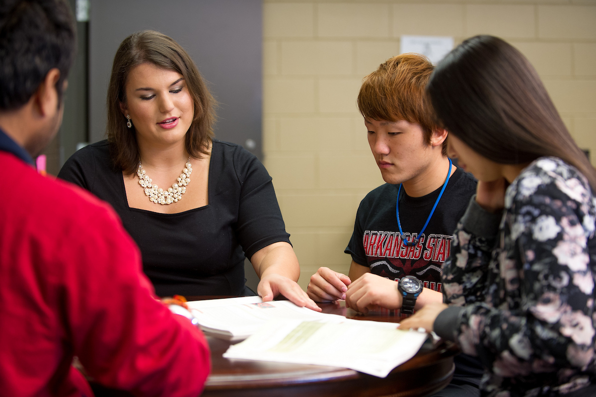 A-State students in a small group discussion with an instructor reviewing documents.