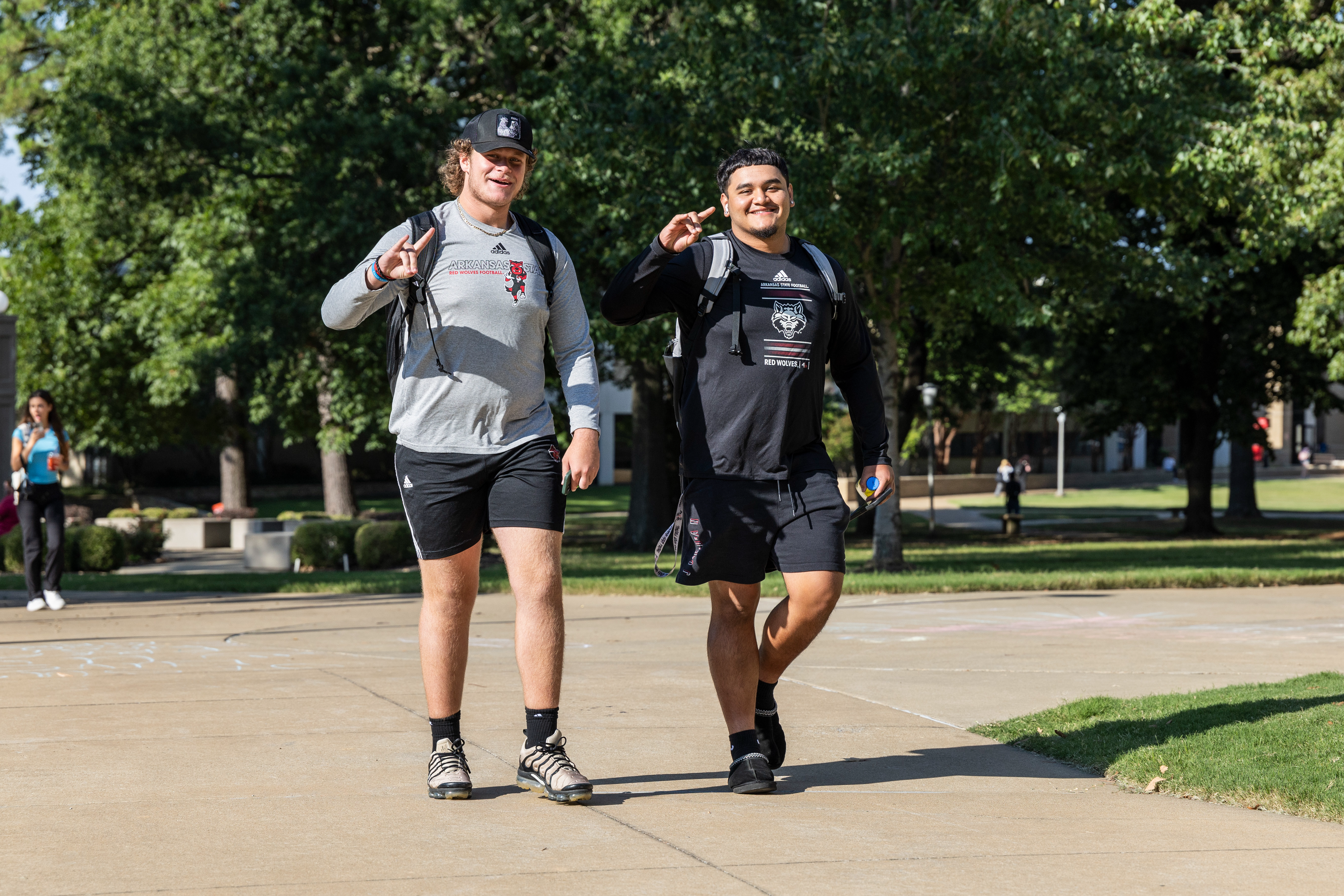 Two students giving a Wolves Up as they walk to class.