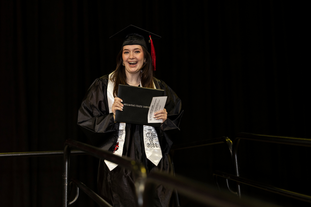 A joyful graduate holds her diploma during a commencement ceremony.