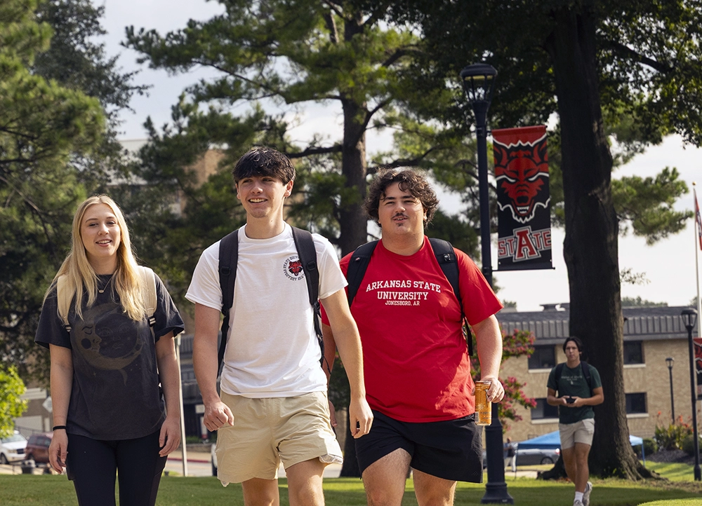 Three students walking on campus.