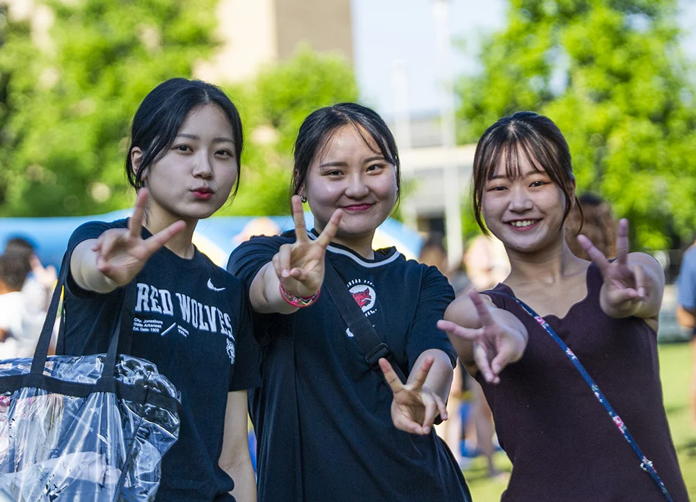 Three exchange students giving peace signs.