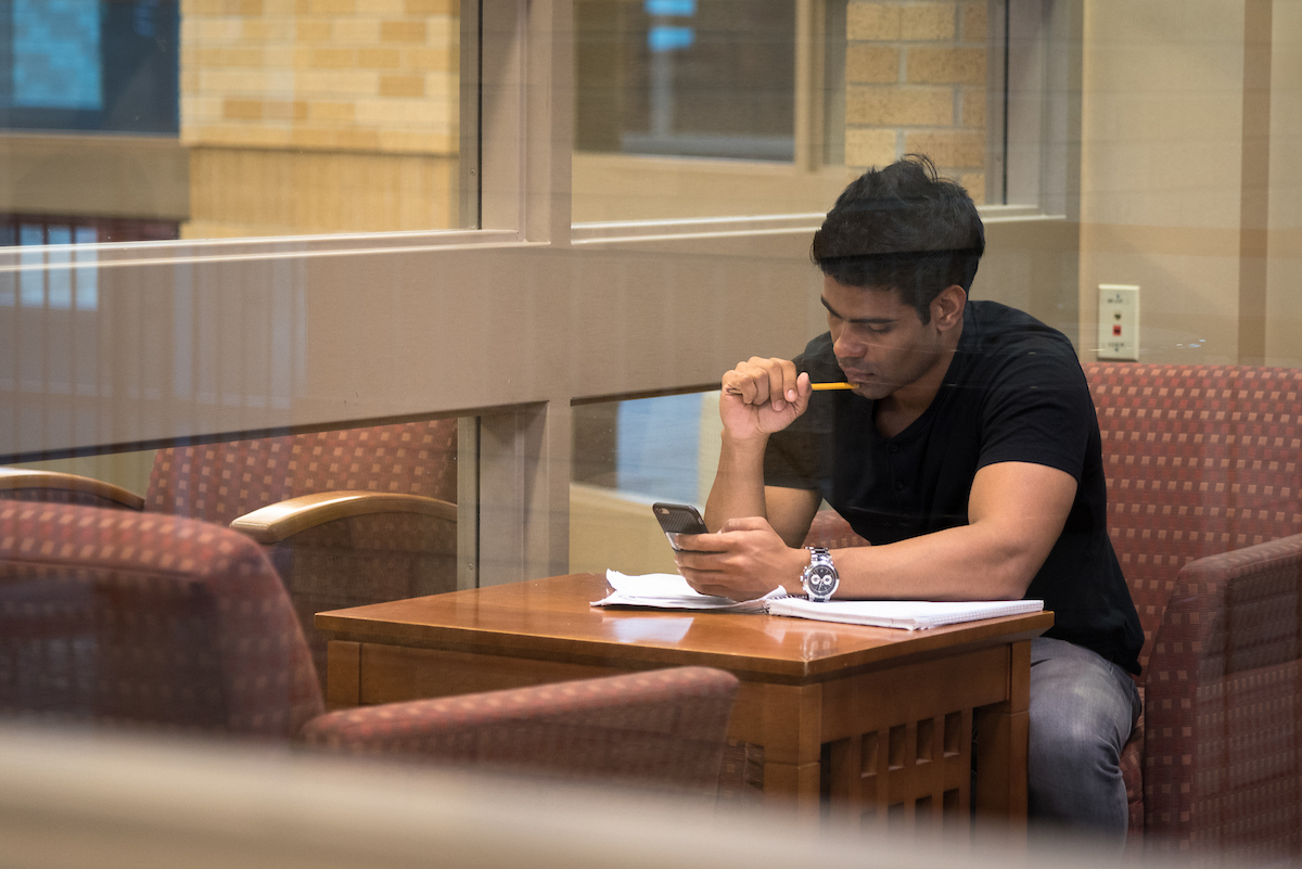 Nontraditional student studying in the Union with phone, pencil, and papers.