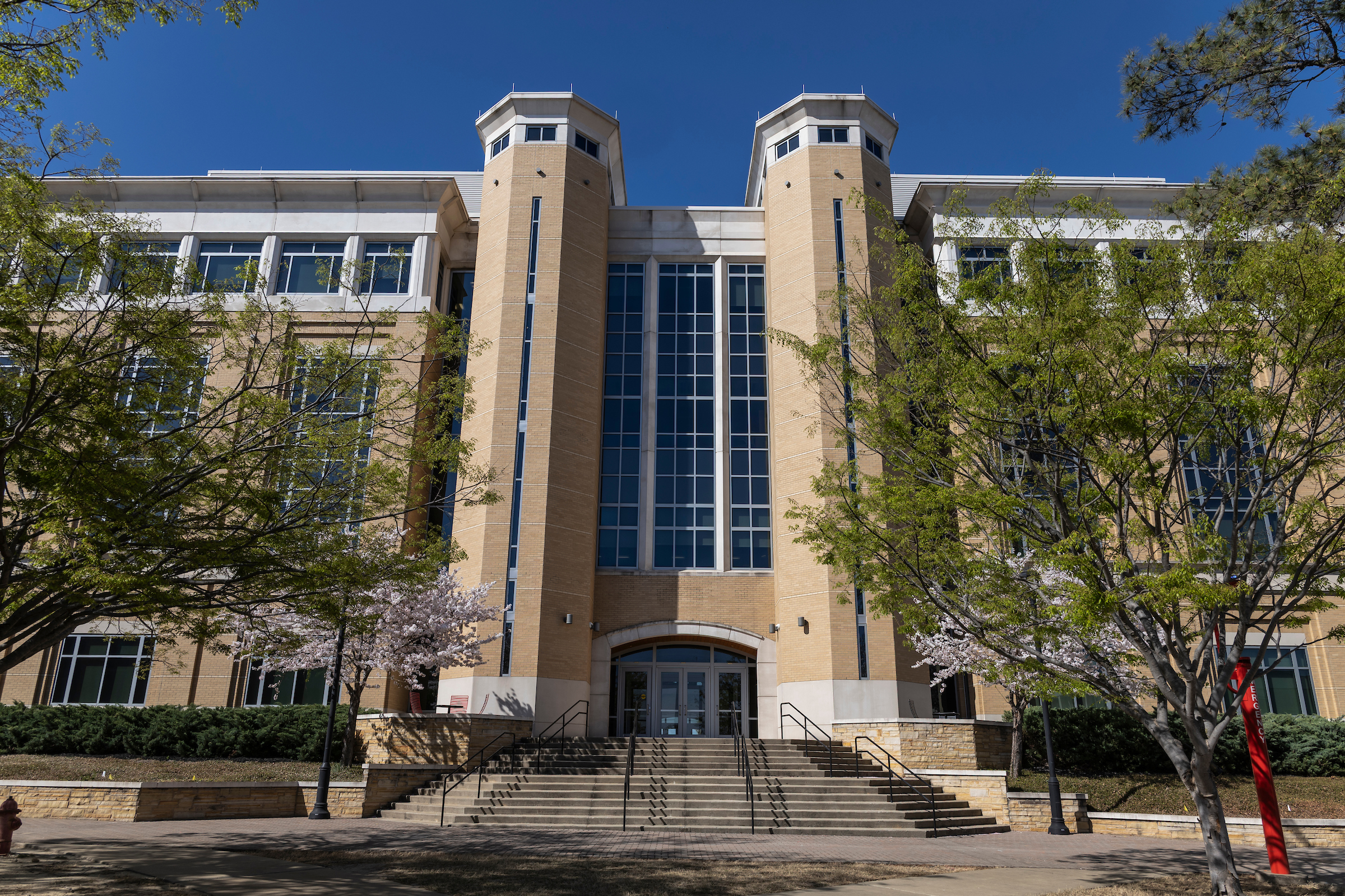Front view of a large Arkansas State University campus building with spring trees.