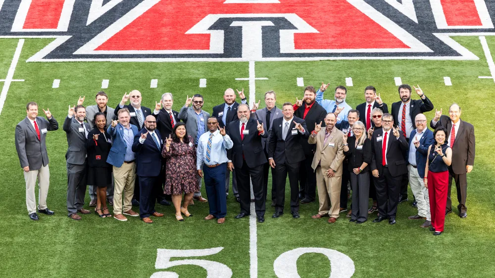 Alumni taking a group photo on the football field.