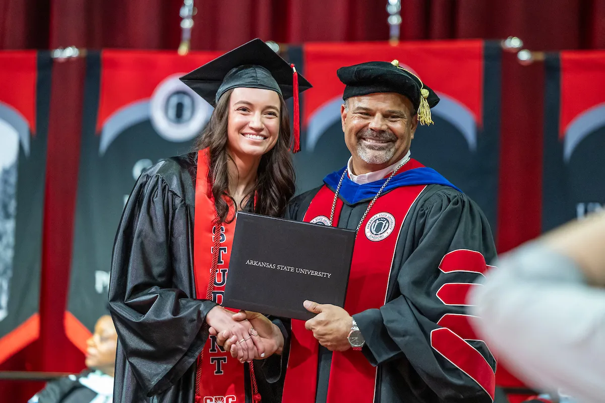 Dr. Todd Shields shaking graduate's hand at ceremony.