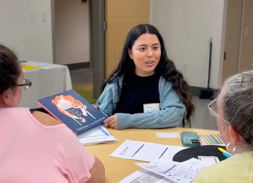 Woman in training, reading a children's book to other adults