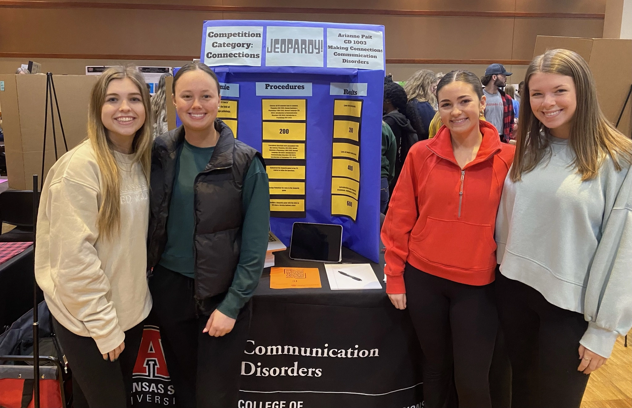 A-State communication disorders students standing by their project at an event.