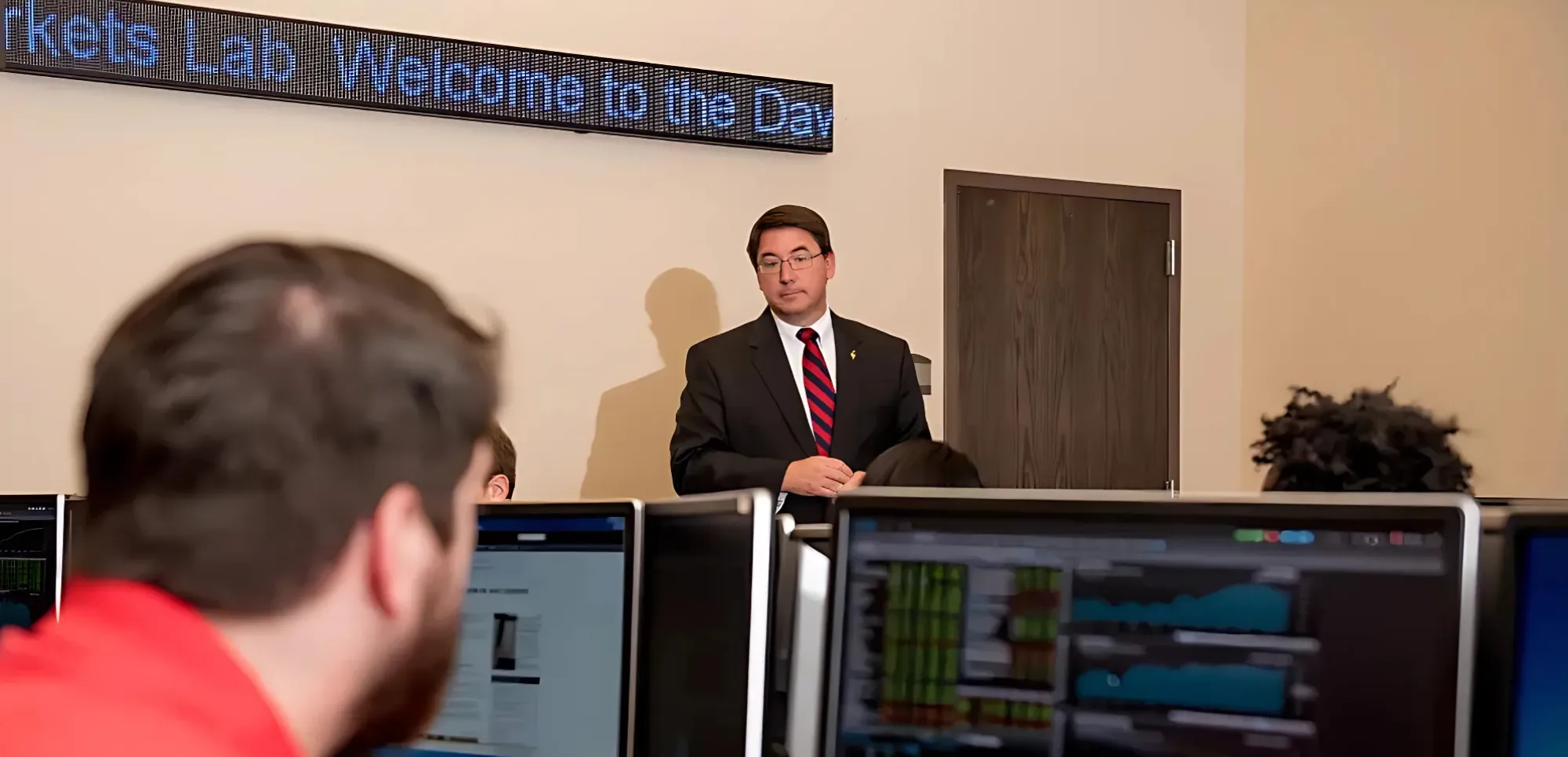 A-State professor teaching business class with tables of students.