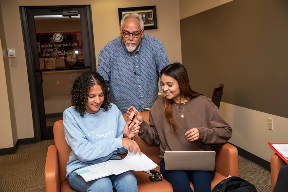 Professor and student going over finance work on a computer in the econ lab.