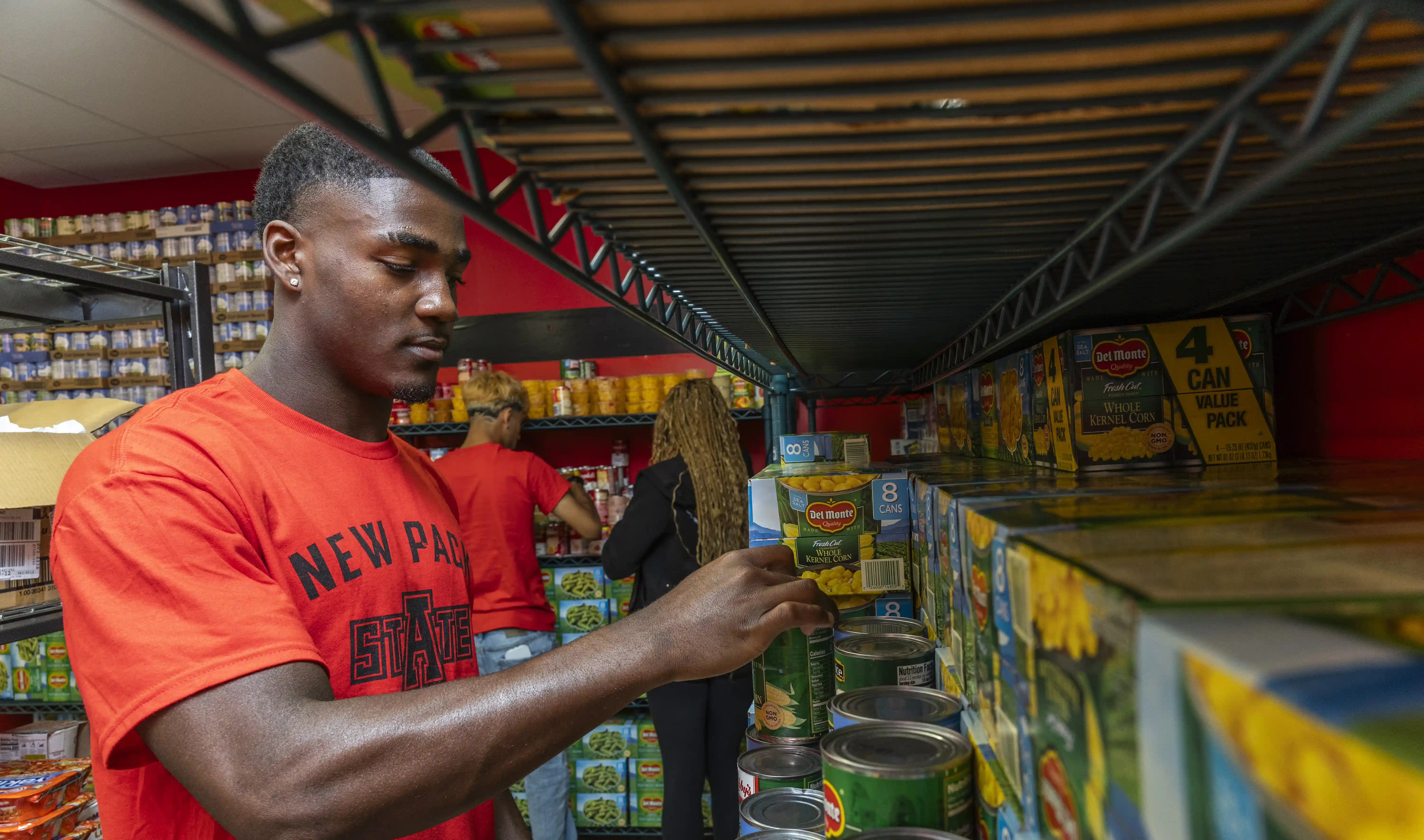Student putting canned food on shelf at A-State Food Pantry.