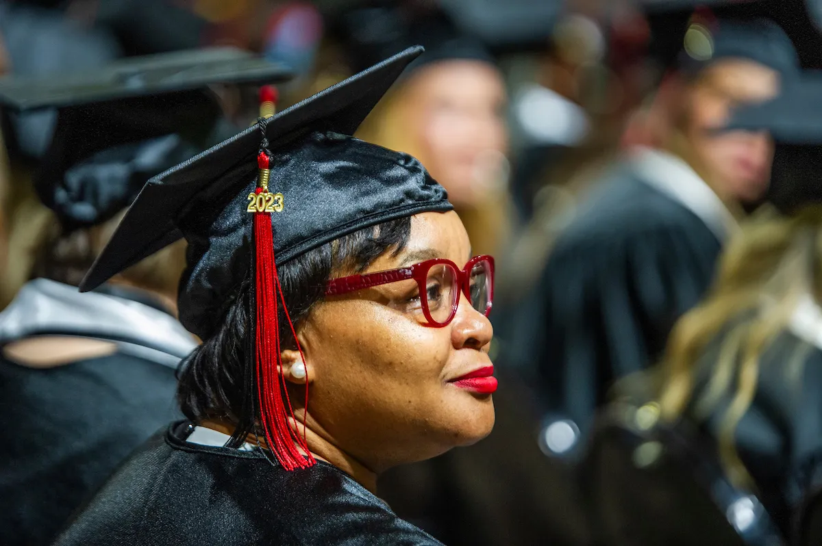 A non-traditional student looks proudly to her family at commencement.