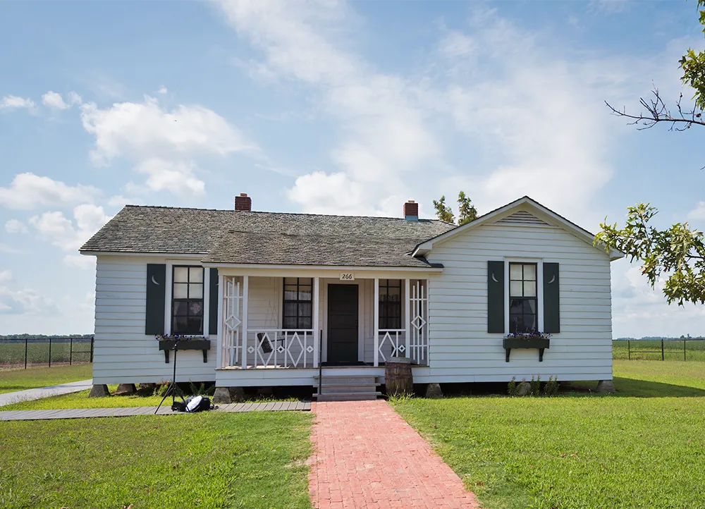 a small home sits in a field with a centered walkway leading to the front door