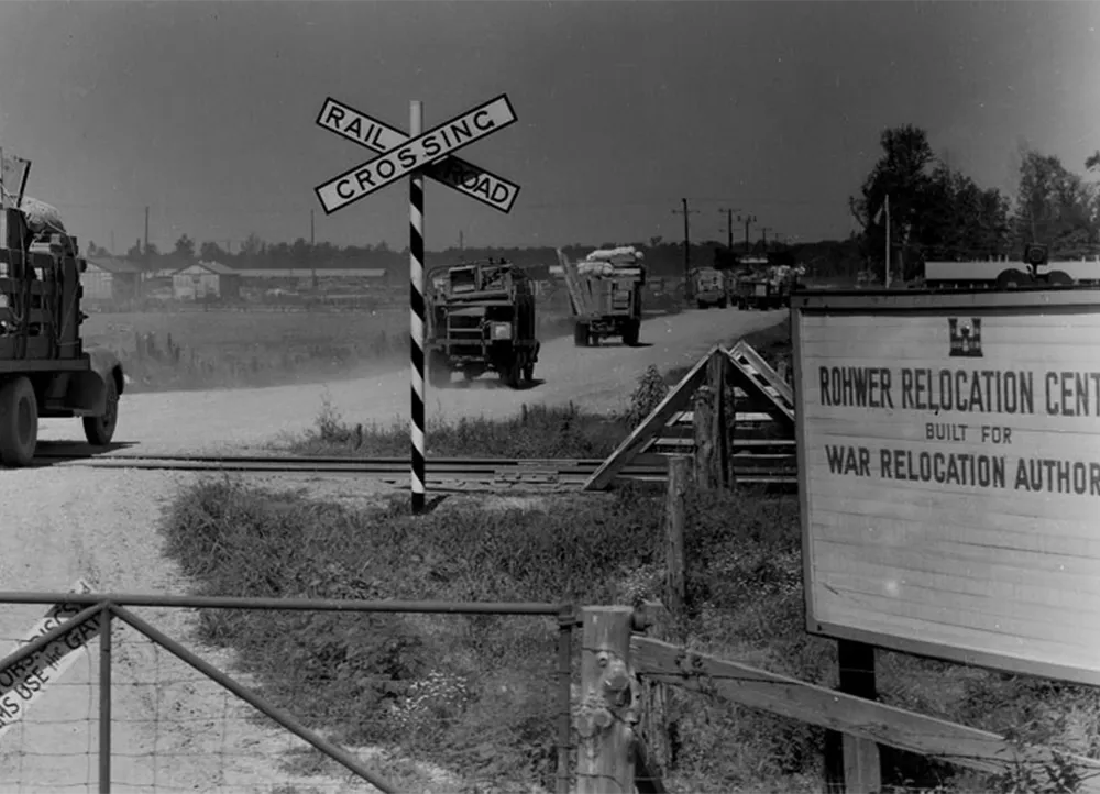 Trucks passing by a sign that reads Rohwer Relocation Center