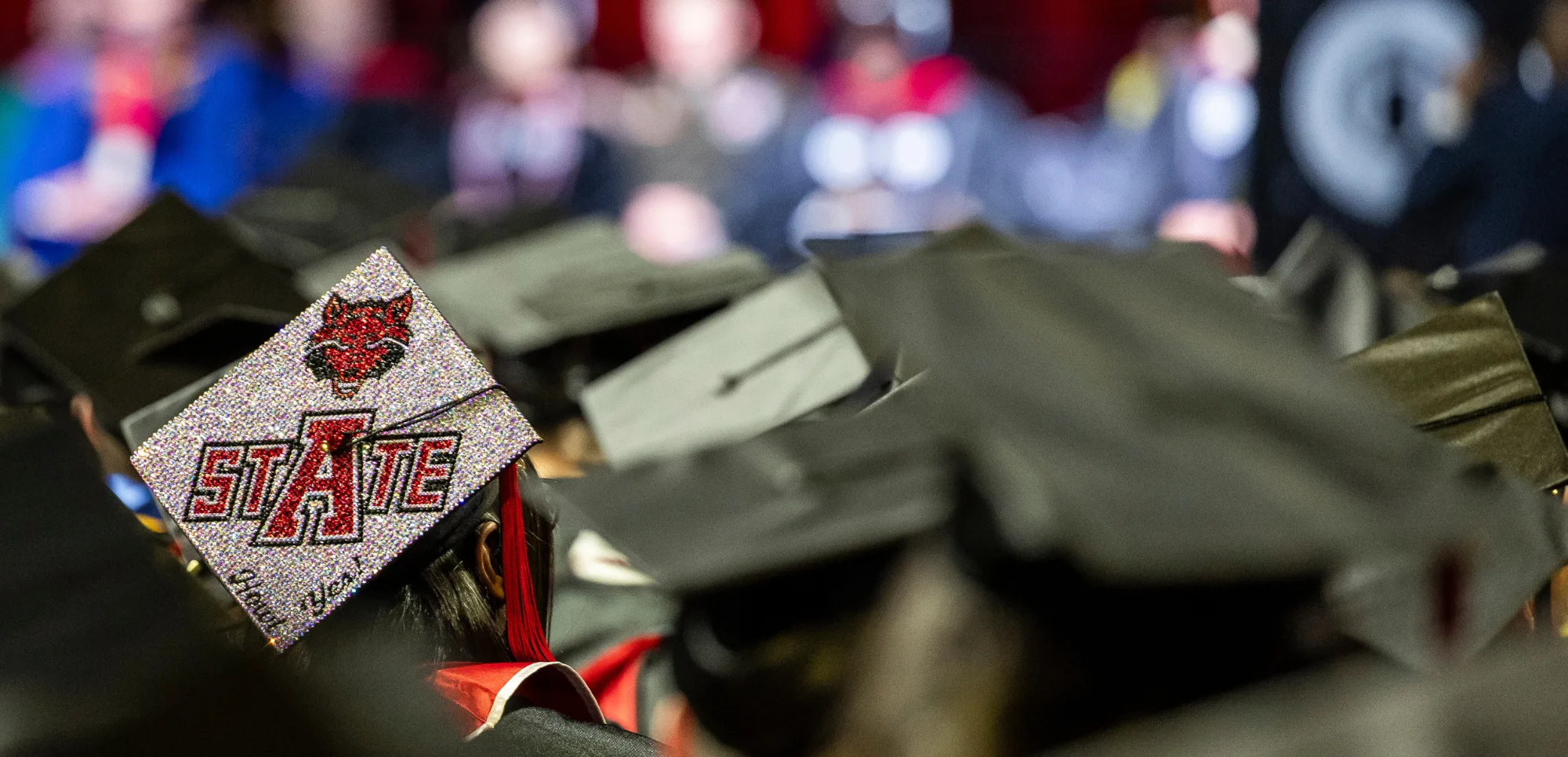 A-State graduation cap with howl yes and glitter on it.