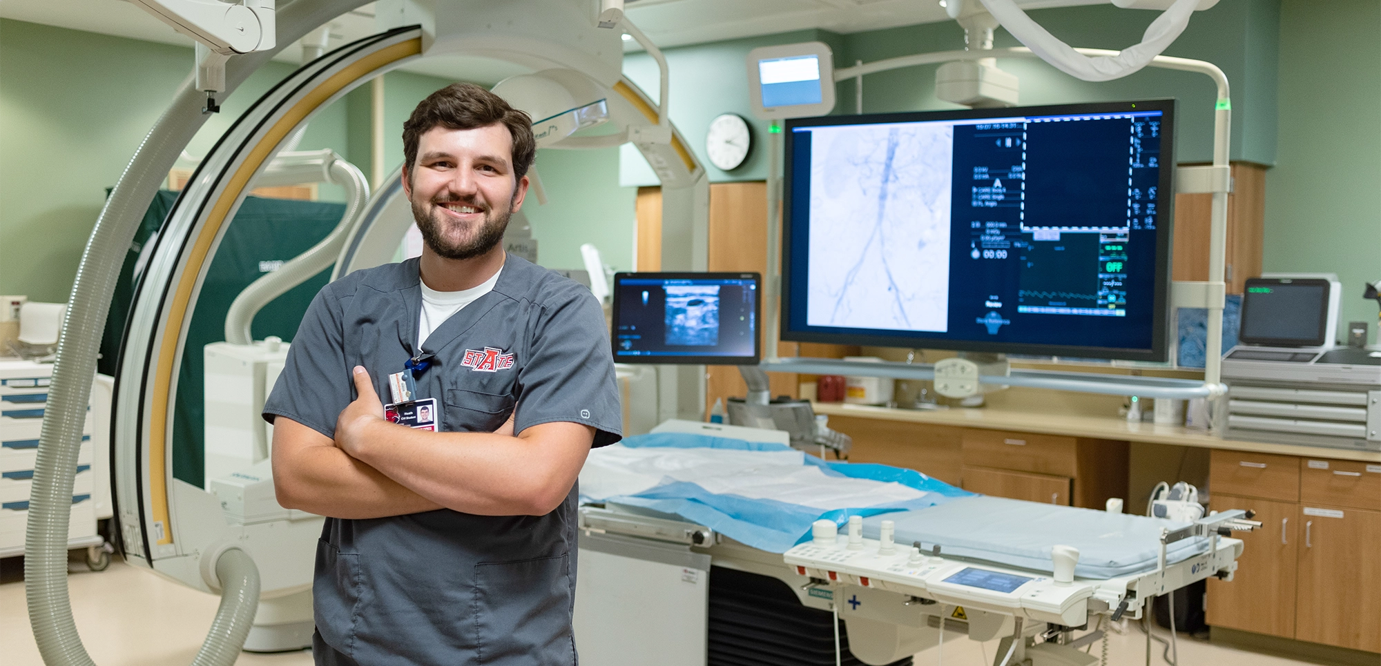 Radiologic Sciences student posing by machine for cardiovascular intervention.