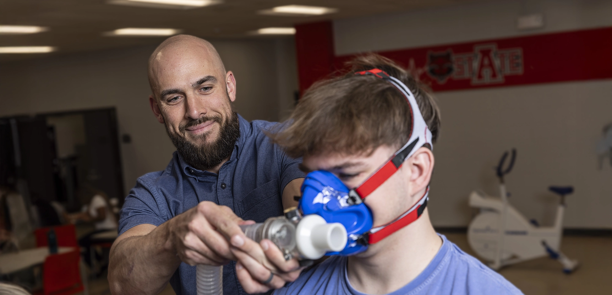 A professor monitoring the breathing of an exercising student.