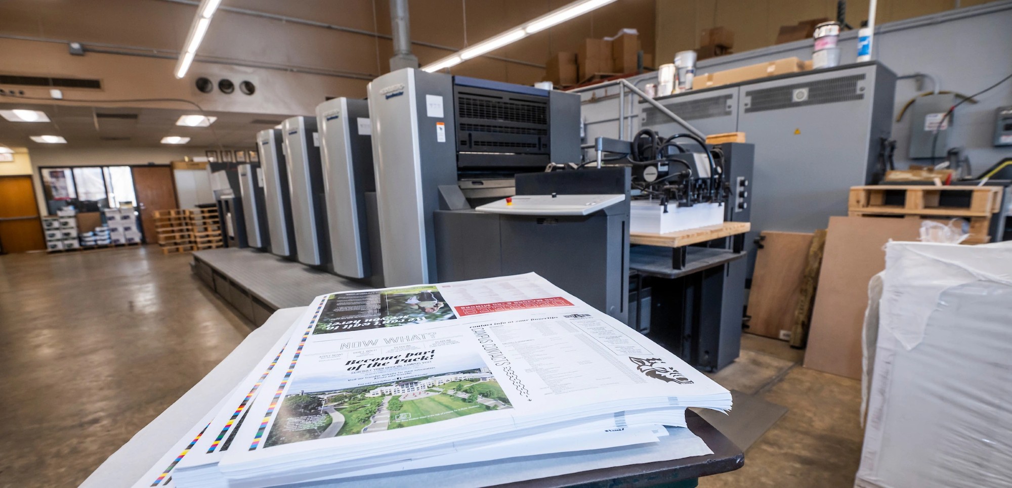 Prints stacked up on a table in front of printing equipment