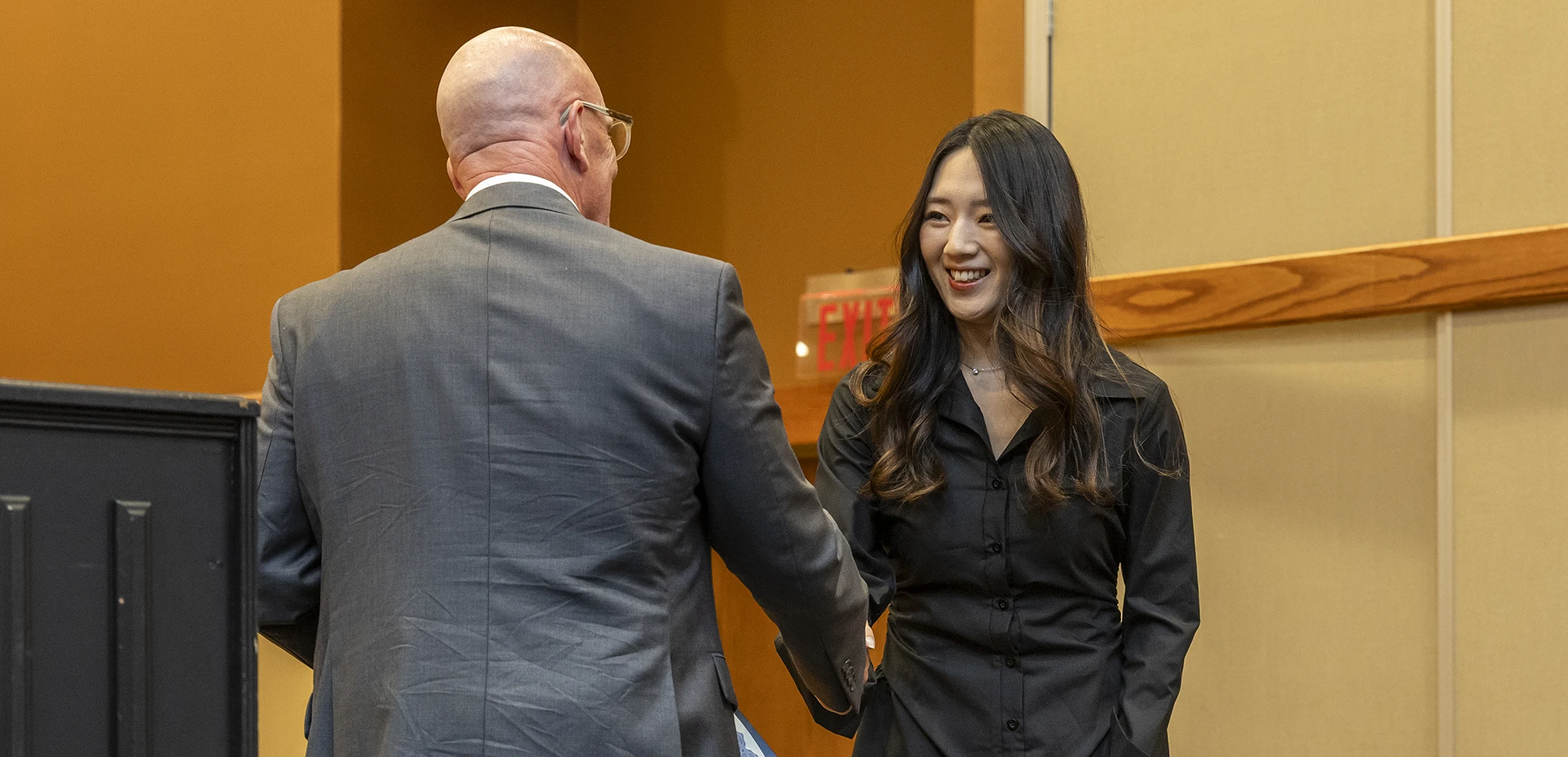 A student in formal wear shaking hands with a man in a suit.