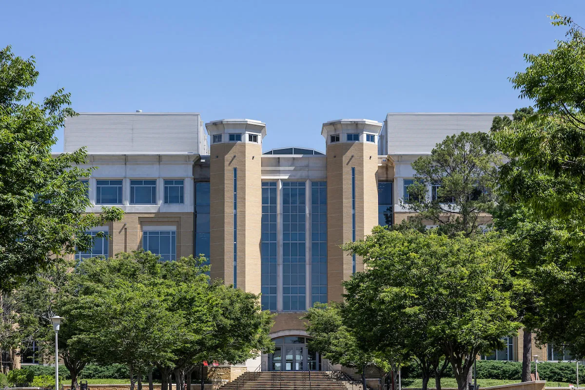 Front view of the Humanities and Social Sciences Building framed by trees on a clear summer day.
