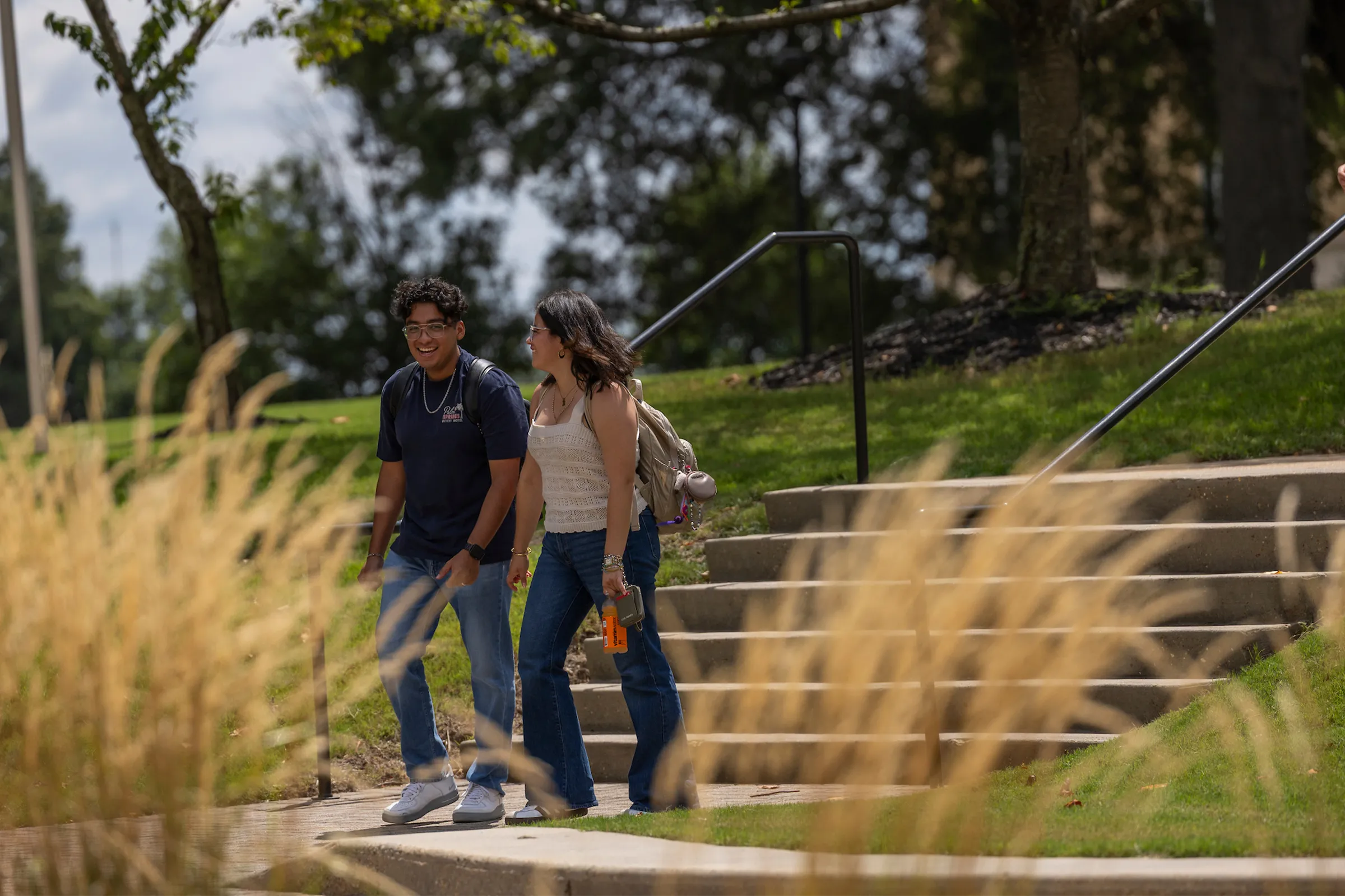 smiling students walking across campus on a sunny day