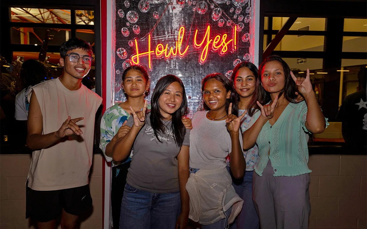 international students giving the wolves-up sign at a silent disco event