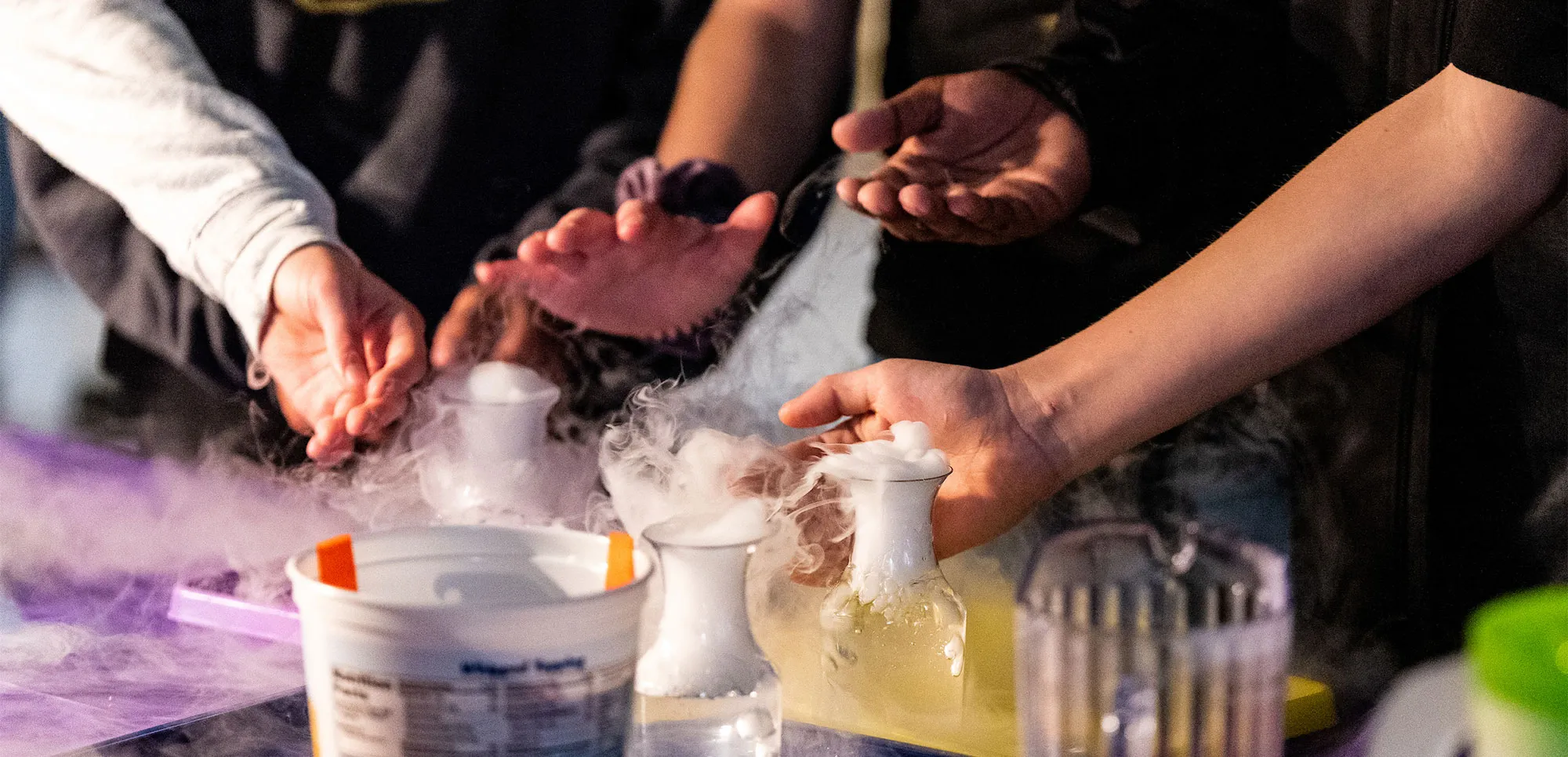 students experimenting with glass beakers that have a smoking liquid coming out
