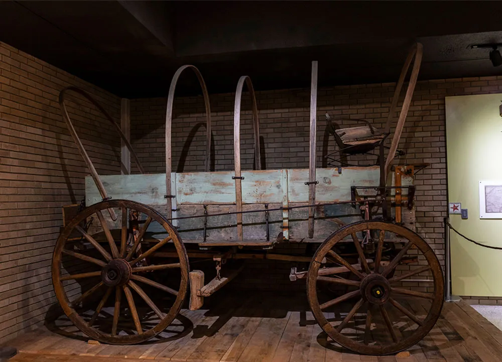 wooden wagon with large wheels and iron supports for a cloth cover