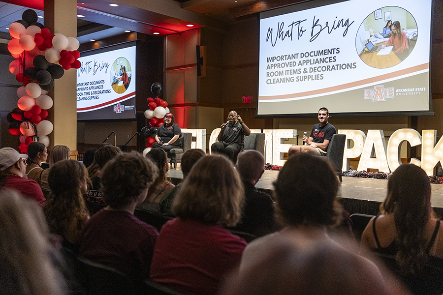 Staff sitting on stage in front of crowd, leading an interest session at New Student Orientation.
