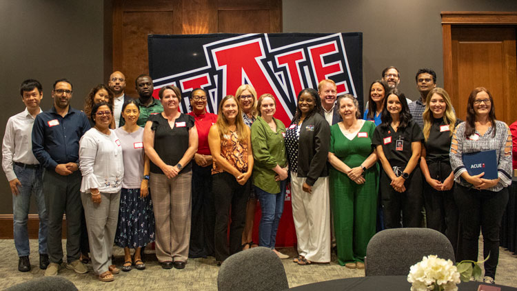Pepole standing in front of A-State banner