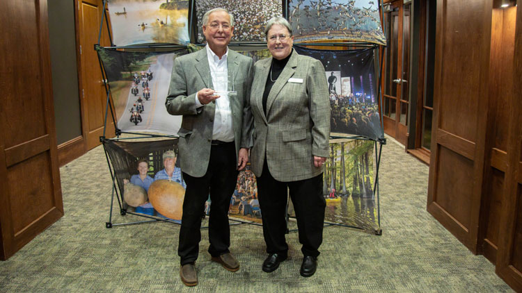 Two people standing together as an award is presented